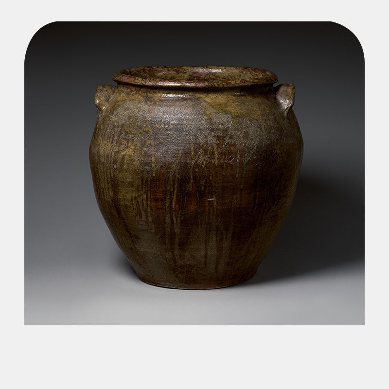 A brown jar with words inscribed at the rim.